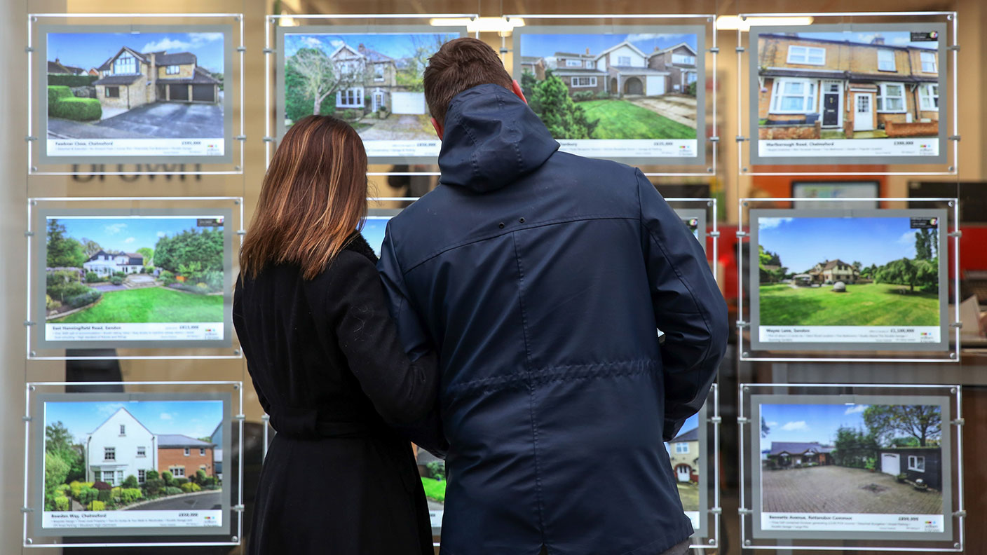 A couple looking at houses in an estate agent&#039;s window