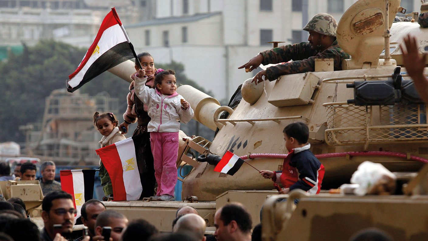 Kids standing on a tank in Tahrir Square, waving Egyptian flags