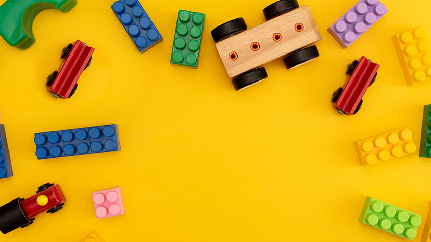 Duplo bricks and toy trains on a yellow background