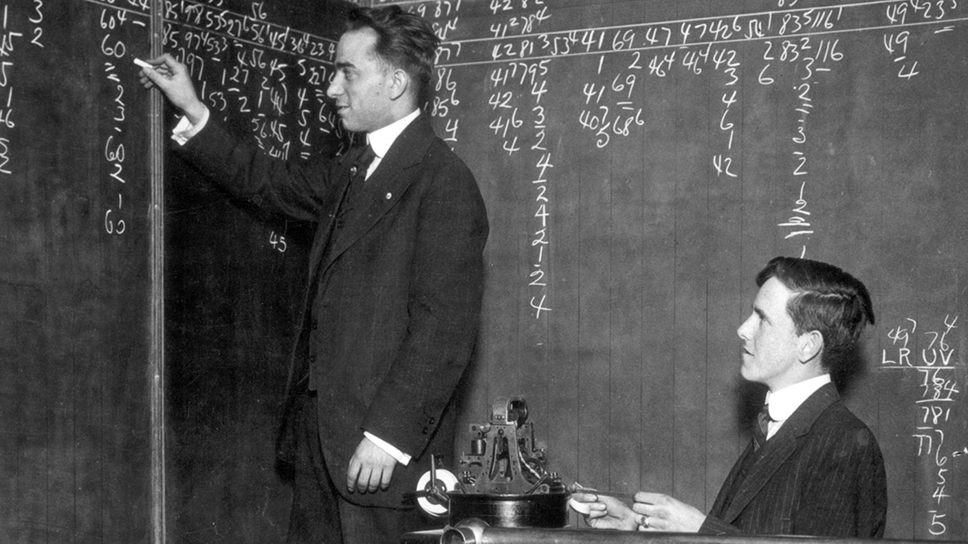 Two men writing figures on a blackboard