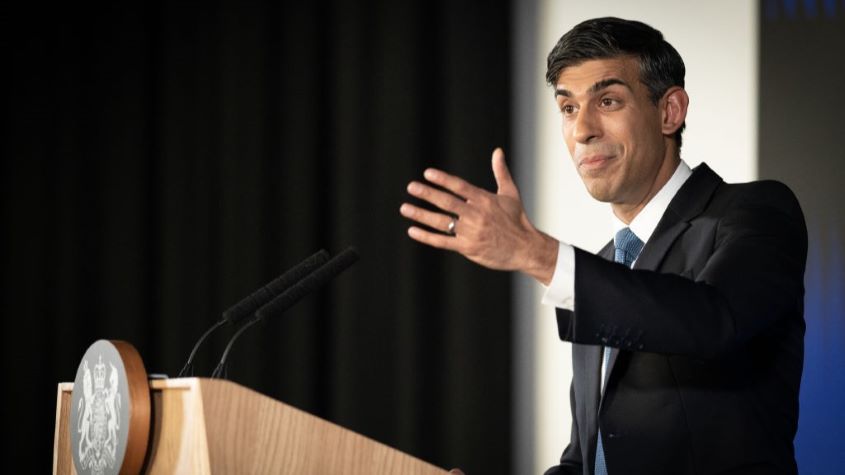 Prime Minister Rishi Sunak gesturing while standing at a podium