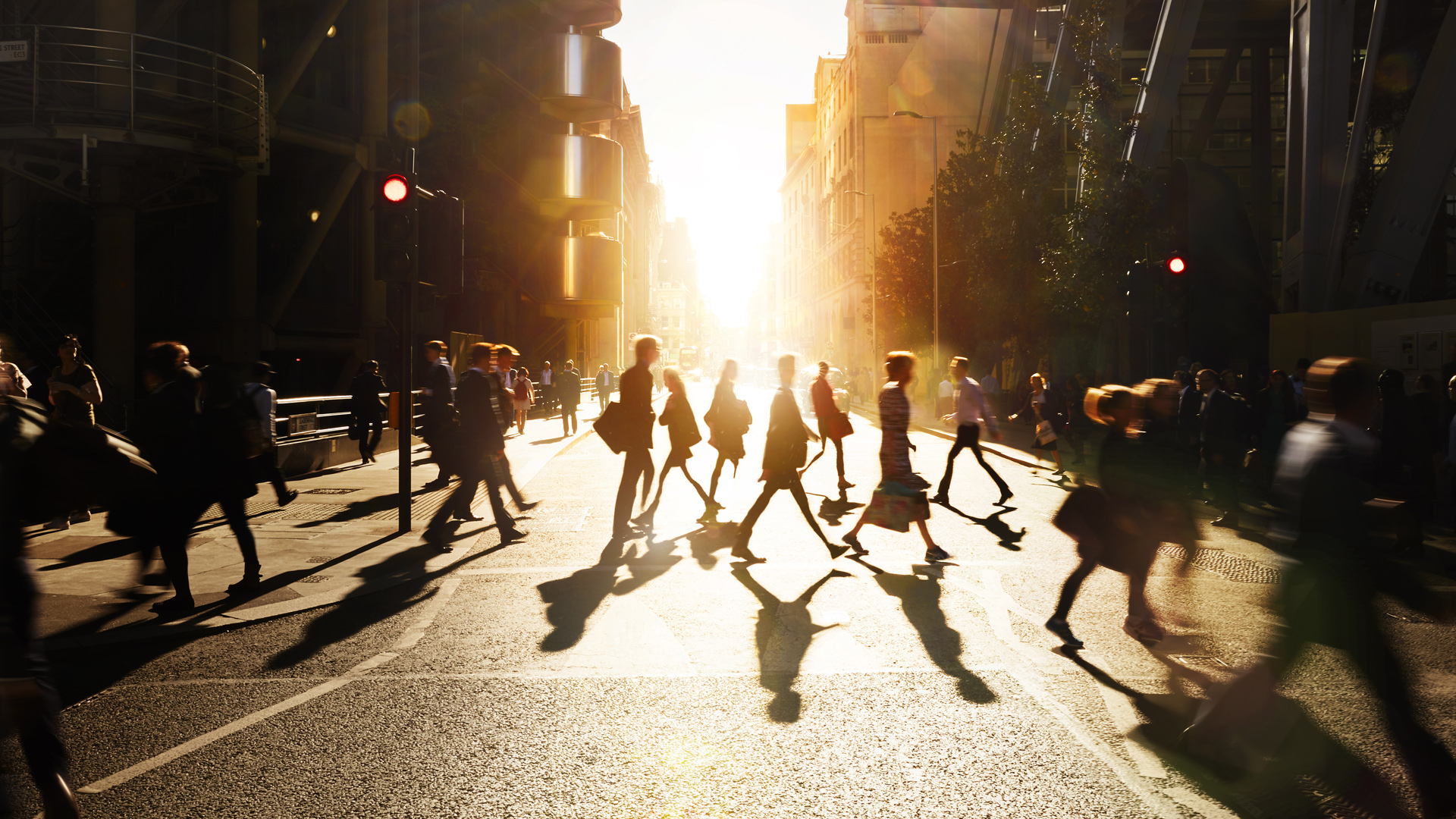 People crossing the street with the sun rising in the background