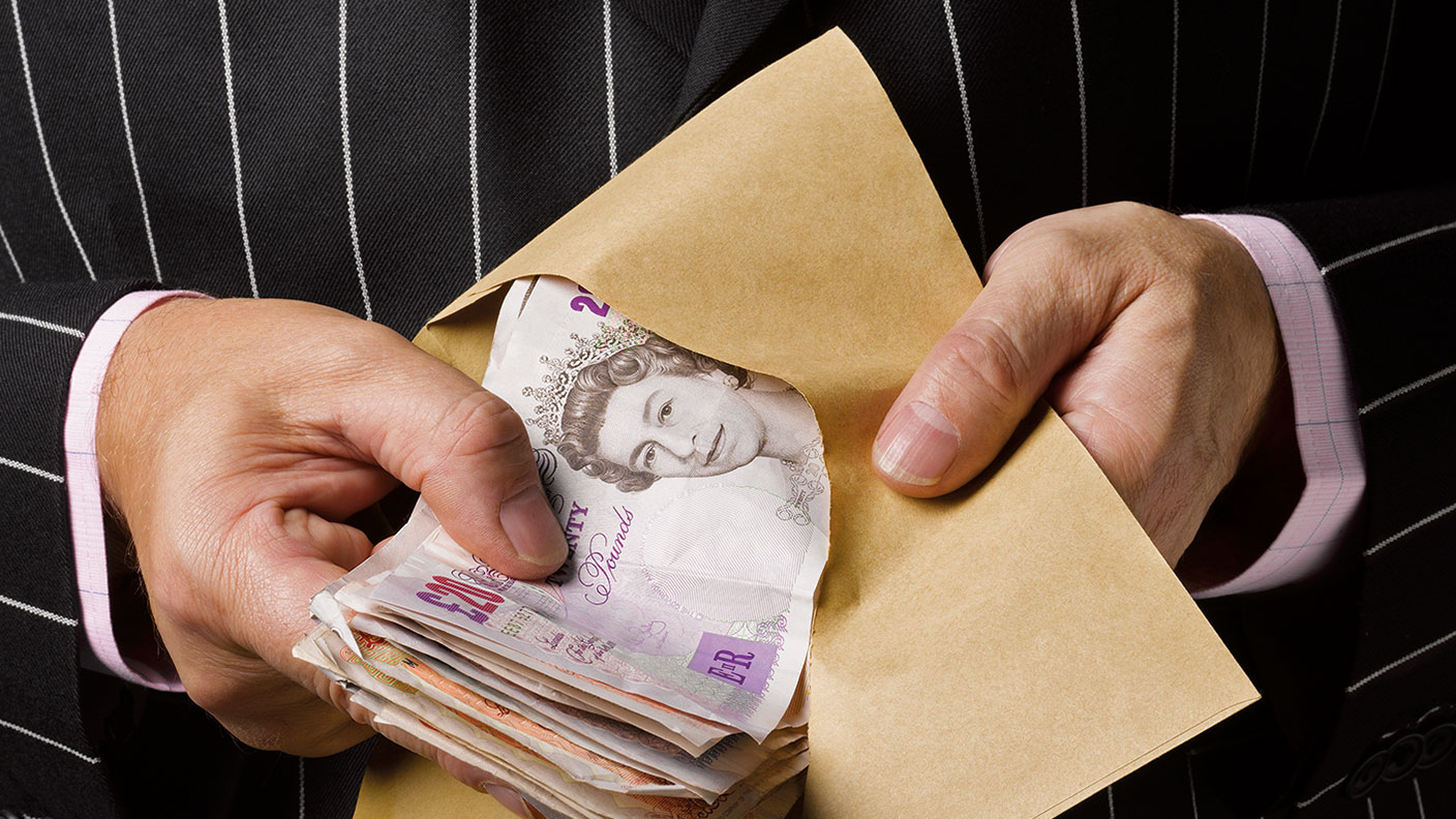 Businessman holding envelope of cash © Getty Images