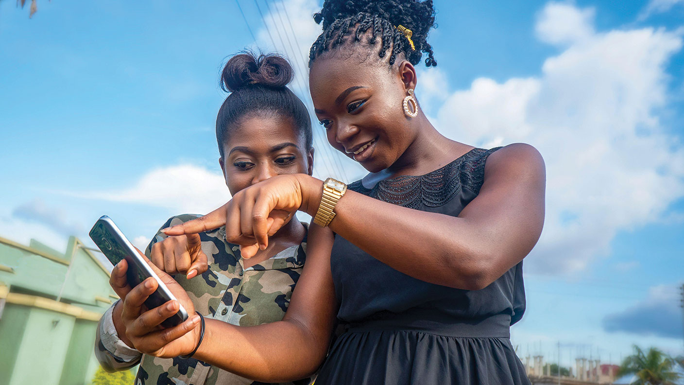 Two African women pointing at a mobile phone 