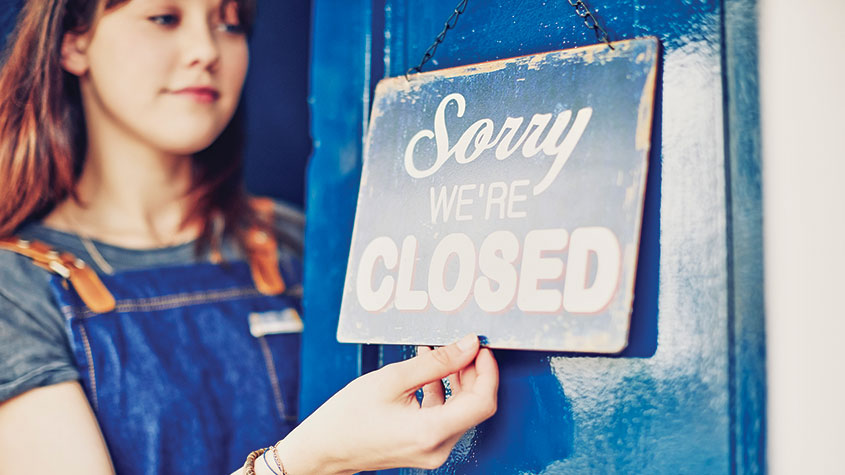 Woman hanging &quot;closed&quot; sign on door