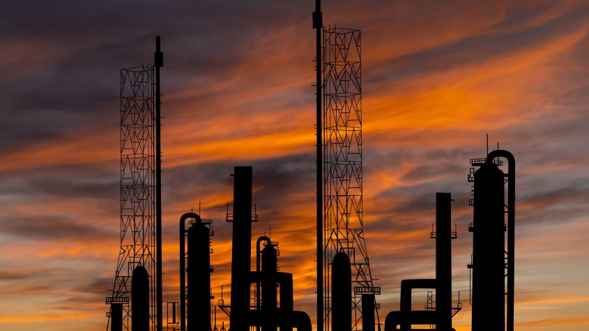 Oil refinery plant silhouetted against sunset