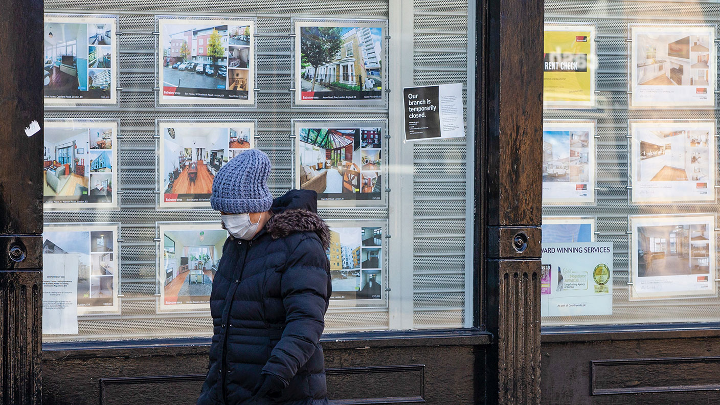A pedestrian with a face mask passes a closed estate agent ©