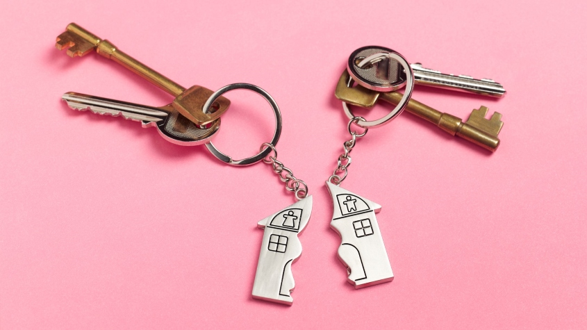 Two sets of house keys on a pink background