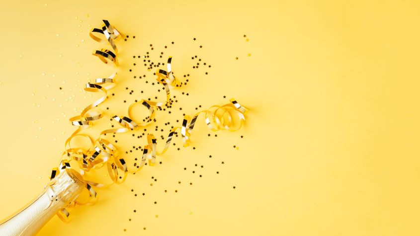 Champagne Bottle With Confetti On Yellow Background