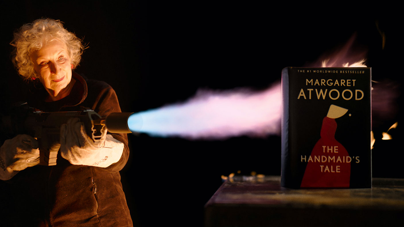 Margaret Atwood burning a book with a flame-thrower
