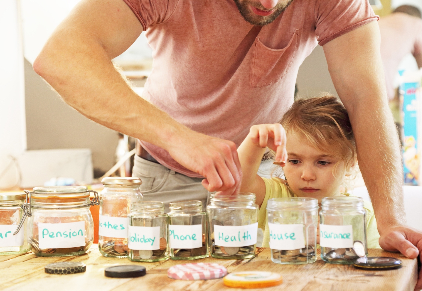 A child and his parent putting coins into different glass jars 