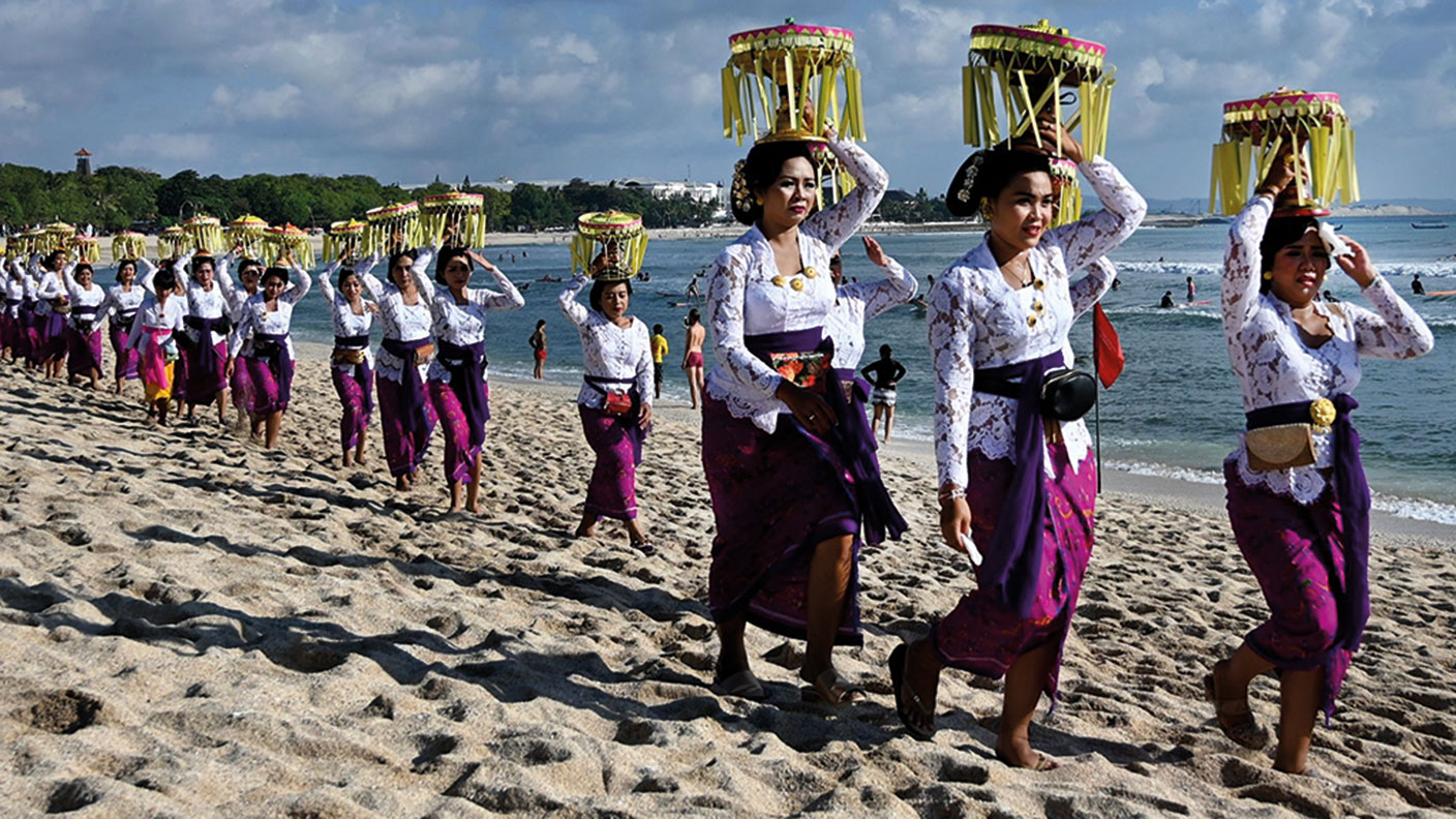 Balinese people walking on a beach for Melasti ceremony prayers