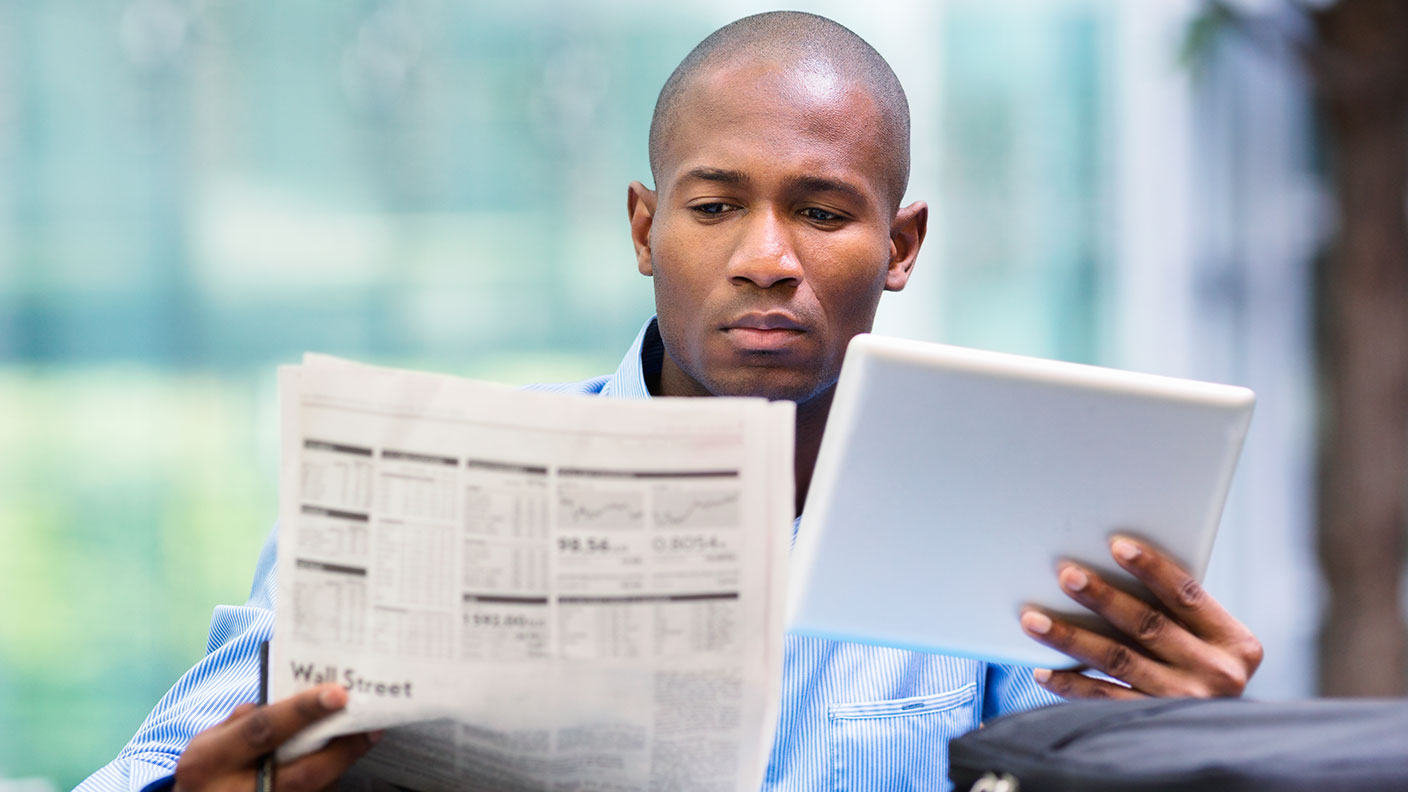 Man reading a newspaper and a tablet